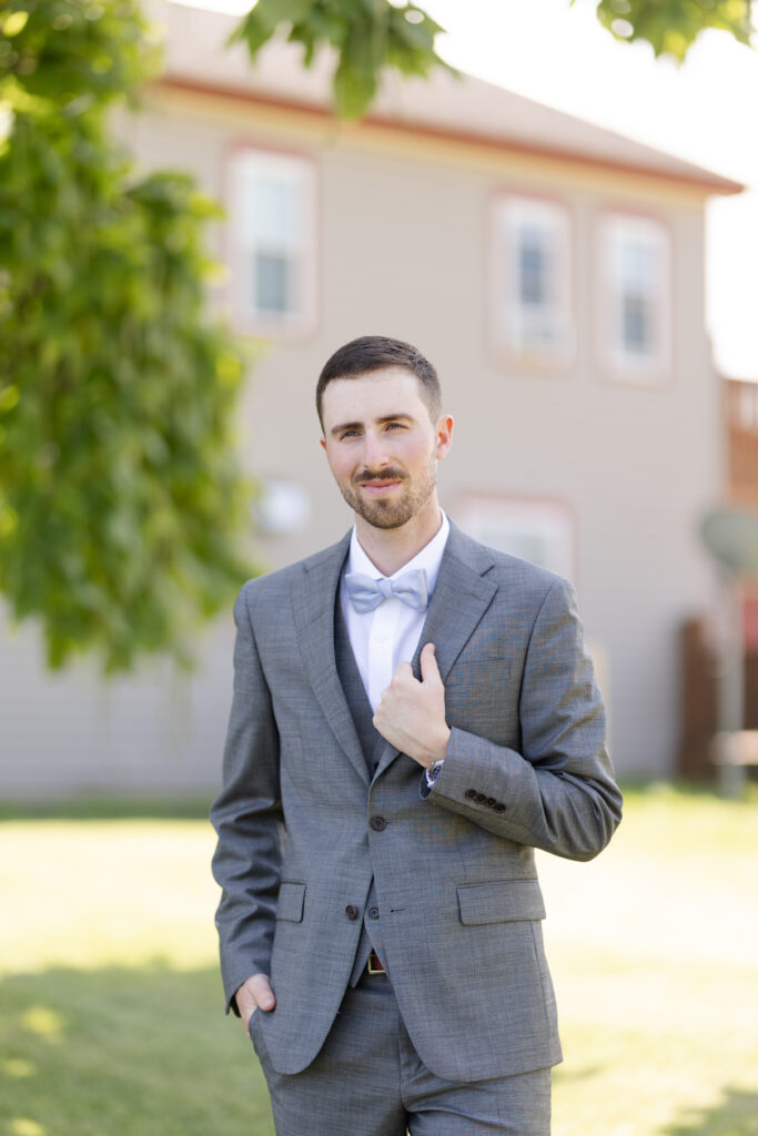 Portrait of groom holding his lapel while looking at the camera. 