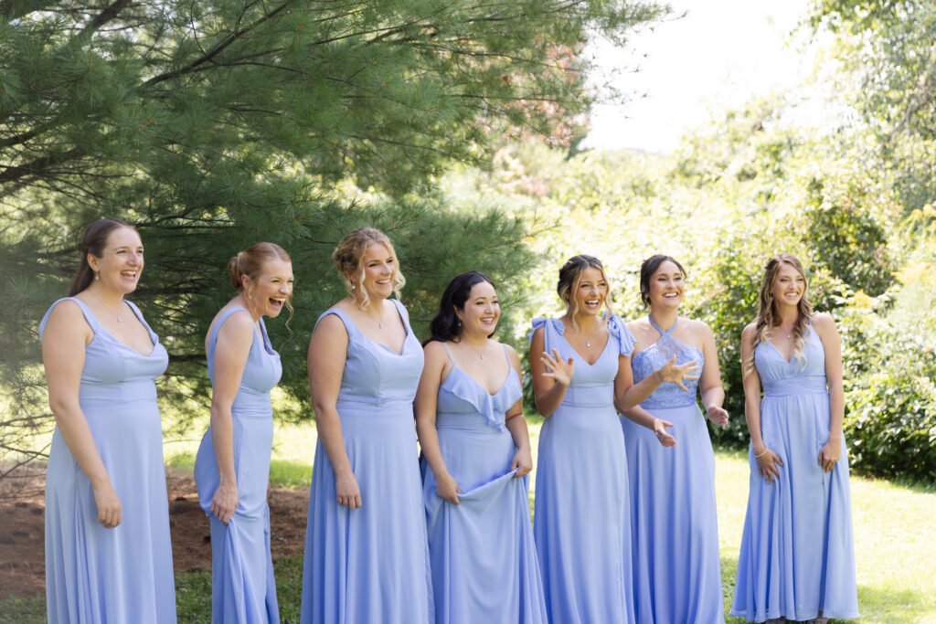 Bridesmaids smile and laugh as they see the bride in her dress for the first time. 