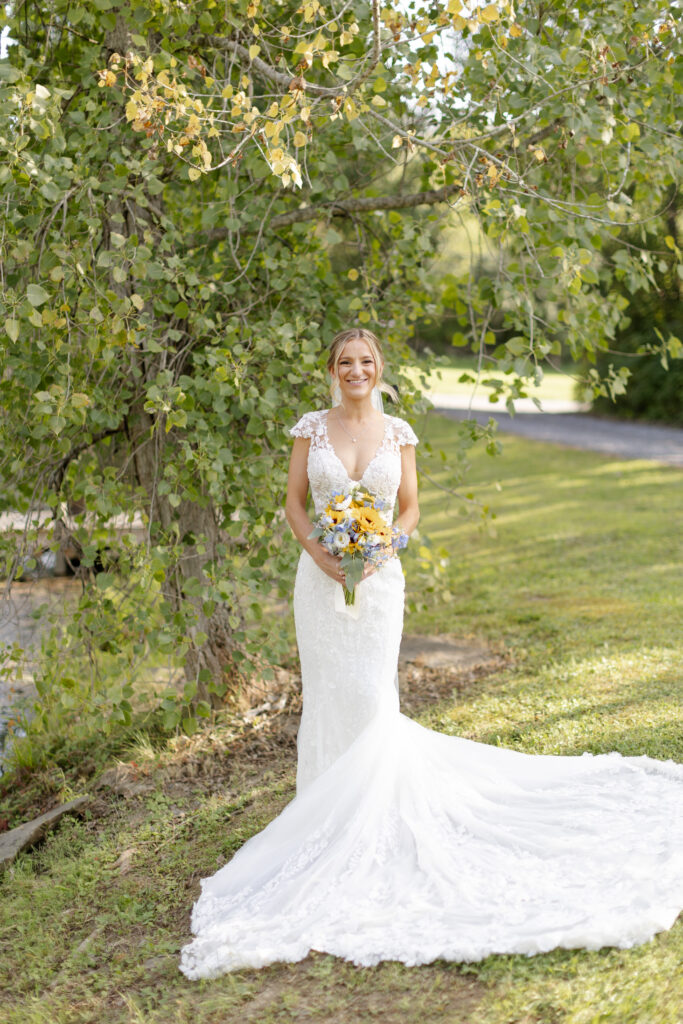 Portrait of bride in her wedding dress, holding her bouquet and smiling at the camera. 